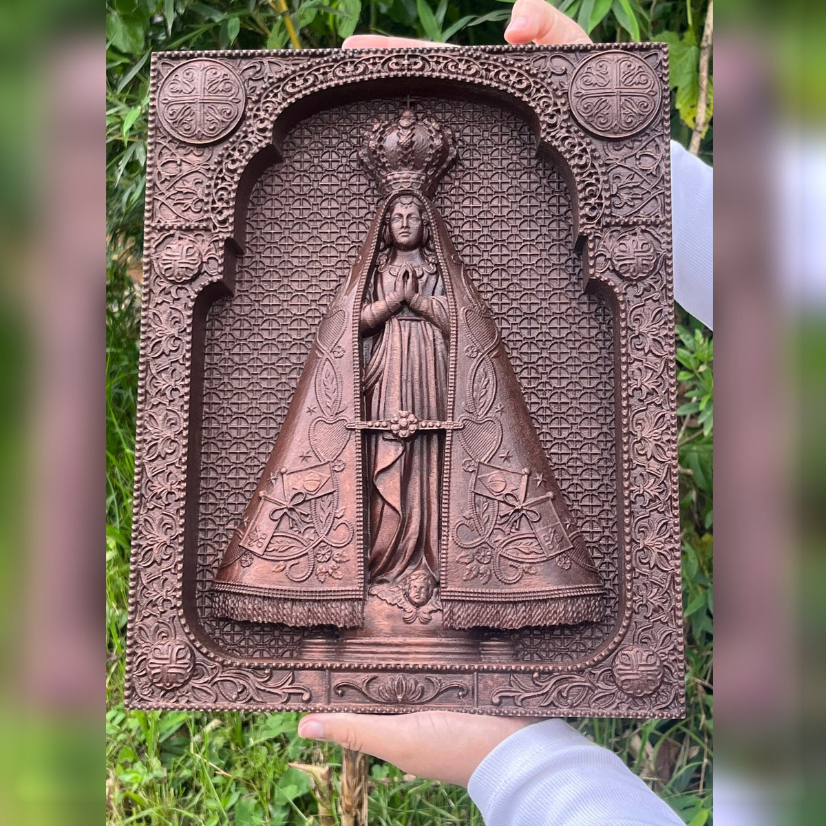 Quadro de Nossa Senhora Aparecida em Madeira marrom de frente, segurado nas mãos - Sagrado Tesouro