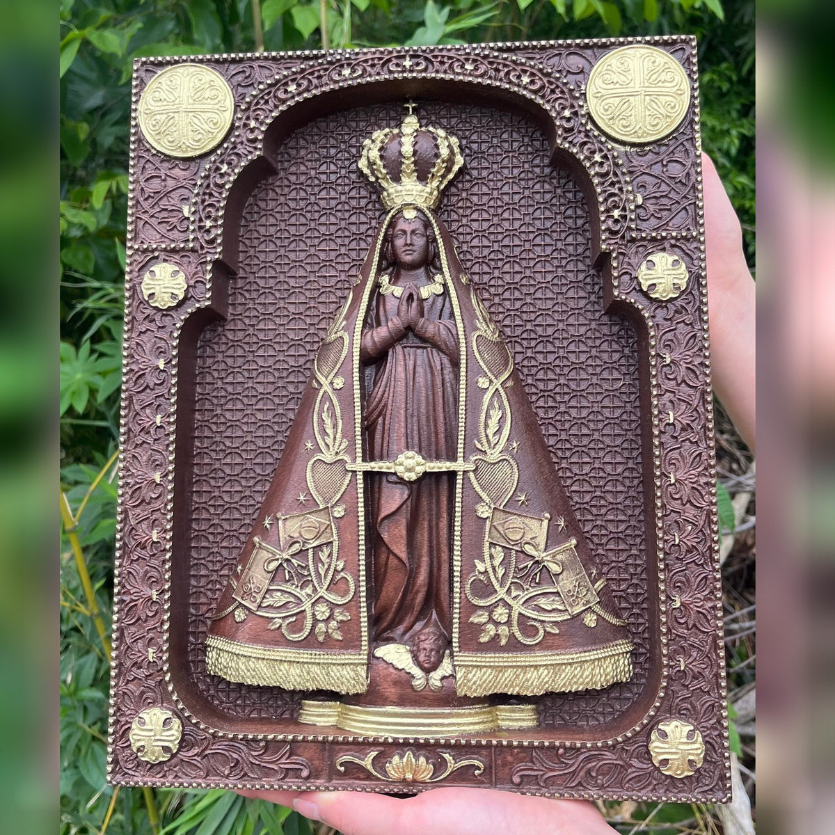 Quadro de Nossa Senhora Aparecida em Madeira dourado de frente, segurado nas mãos - Sagrado Tesouro